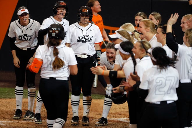 Oklahoma State infielder Karli Godwin (14) is greeted at home by teammates after hitting a home run in the sixth inning of a college softball game between the Oklahoma State University Cowgirls and the South Dakota State Jackrabbits, Tuesday, Feb. 27, 2024.