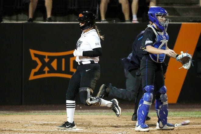 Oklahoma State infielder Micaela Wark (12) runs past South Dakota State's Abby Gentry (24) to score a run in the second softball game of a double header between the Oklahoma State University Cowgirls and the South Dakota State Jackrabbits, Tuesday, Feb. 27, 2024.