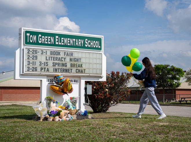 Anabell Gonzalez places balloons on a memorial forming at Tom Green Elementary School in Buda, Texas, Match 23, 2023 after a class was involved in a bus crash that left one student dead the day before.