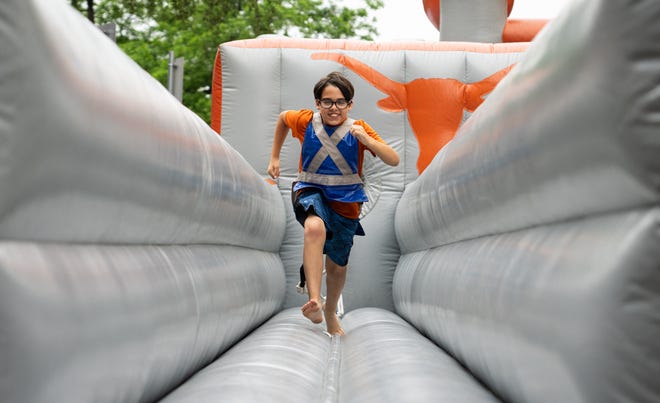 Nico Lozada, 11, from Sugarland, plays on the inflatables on Bevo Boulevard ahead of the Texas Longhorns' spring Orange and White game at Darrell K Royal Texas Memorial Stadium in Austin, Texas, April 20, 2024.