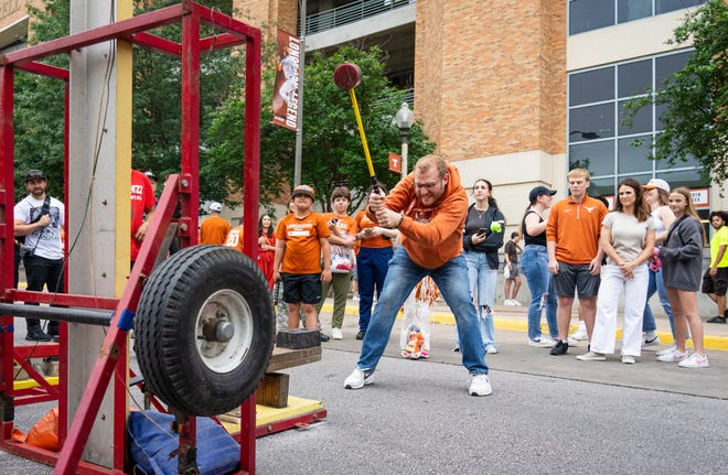 Josh Jacobi, from Fort Worth, swings a hammer while playing games along Smokey's Midway ahead of the Texas Longhorns' spring Orange and White game at Darrell K Royal Texas Memorial Stadium in Austin, Texas, April 20, 2024.