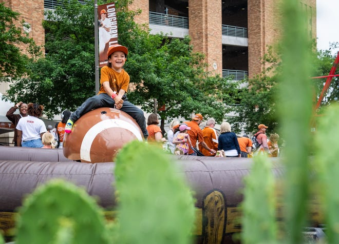 Mayan Mendoza, 6, rides the mechanical football along Smokey's Midway ahead of the Texas Longhorns' spring Orange and White game at Darrell K Royal Texas Memorial Stadium in Austin, Texas, April 20, 2024.