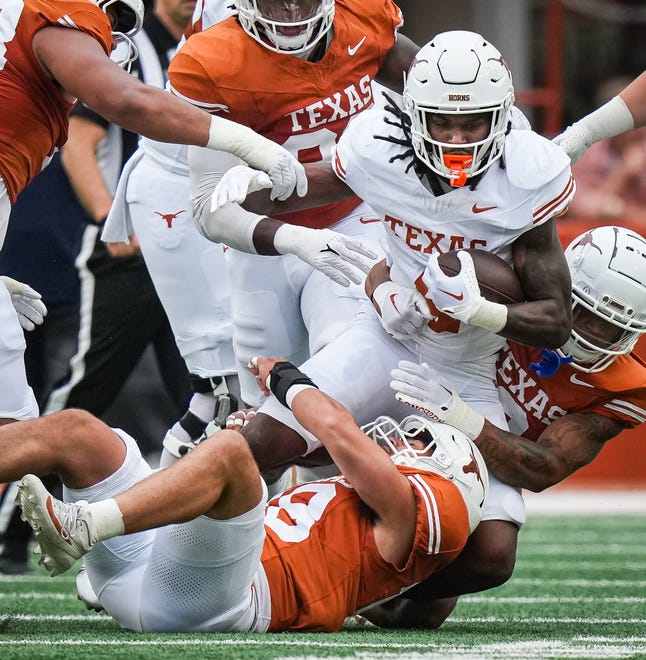 Texas White team running back CJ Baxter (4) is tackled by Texas Orange team defense in the first quarter of the Longhorns' spring Orange and White game at Darrell K Royal Texas Memorial Stadium in Austin, Texas, April 20, 2024.