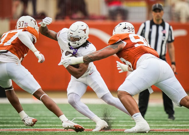 Texas White team running back Jaydon Blue (23) navigates between defense from Texas Orange linebacker Morice Blackwell Jr. (37) and defensive lineman Tiaoalii Savea (98) in the second quarter of the Longhorns' spring Orange and White game at Darrell K Royal Texas Memorial Stadium in Austin, Texas, April 20, 2024.