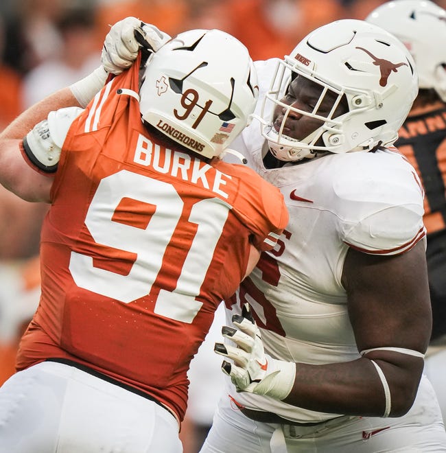 Texas White team offensive lineman Cameron Williams (56) grabs the uniform of Texas Orange team edge Ethan Burke (91) in the second quarter of the Longhorns' spring Orange and White game at Darrell K Royal Texas Memorial Stadium in Austin, Texas, April 20, 2024.