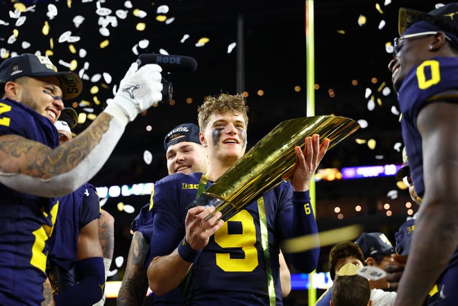 Michigan quarterback J.J. McCarthy holds the national championship trophy after the Wolverines beat Washington in the 2023 title game. Michigan will host Texas Sept. 7 at 11 a.m., Fox Sports announced Saturday.